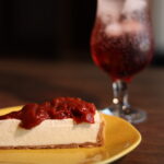 cheesecake com calda de goiabada e soda italiana ao fundo