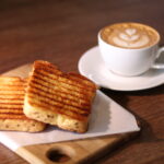 pão brioche na chapa com café latte ao fundo